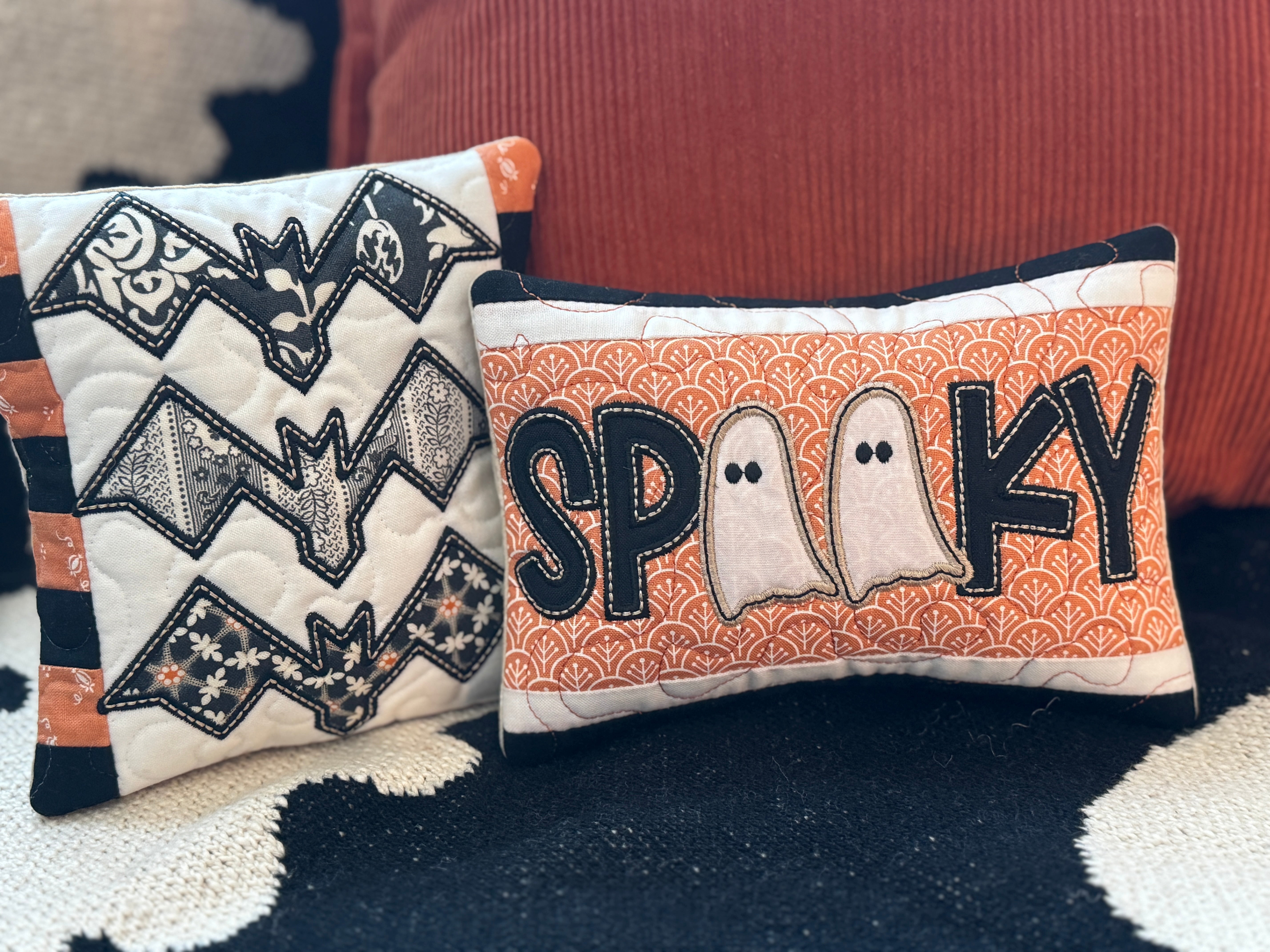 Two Halloween-themed pillows with bat design and 'Spooky' text on a textured surface.