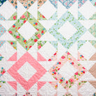 Quilt with floral patterns and a pink diamond shape