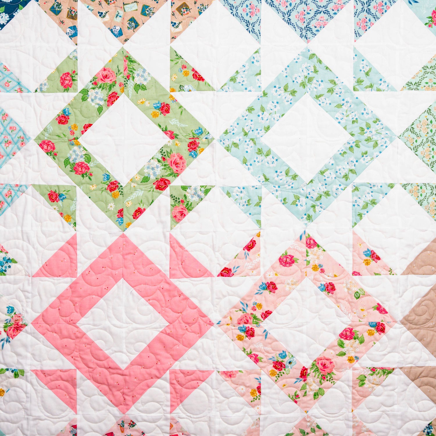 Quilt with floral patterns and a pink diamond shape