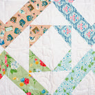 Quilt with diamond pattern featuring various floral fabrics on a white background
