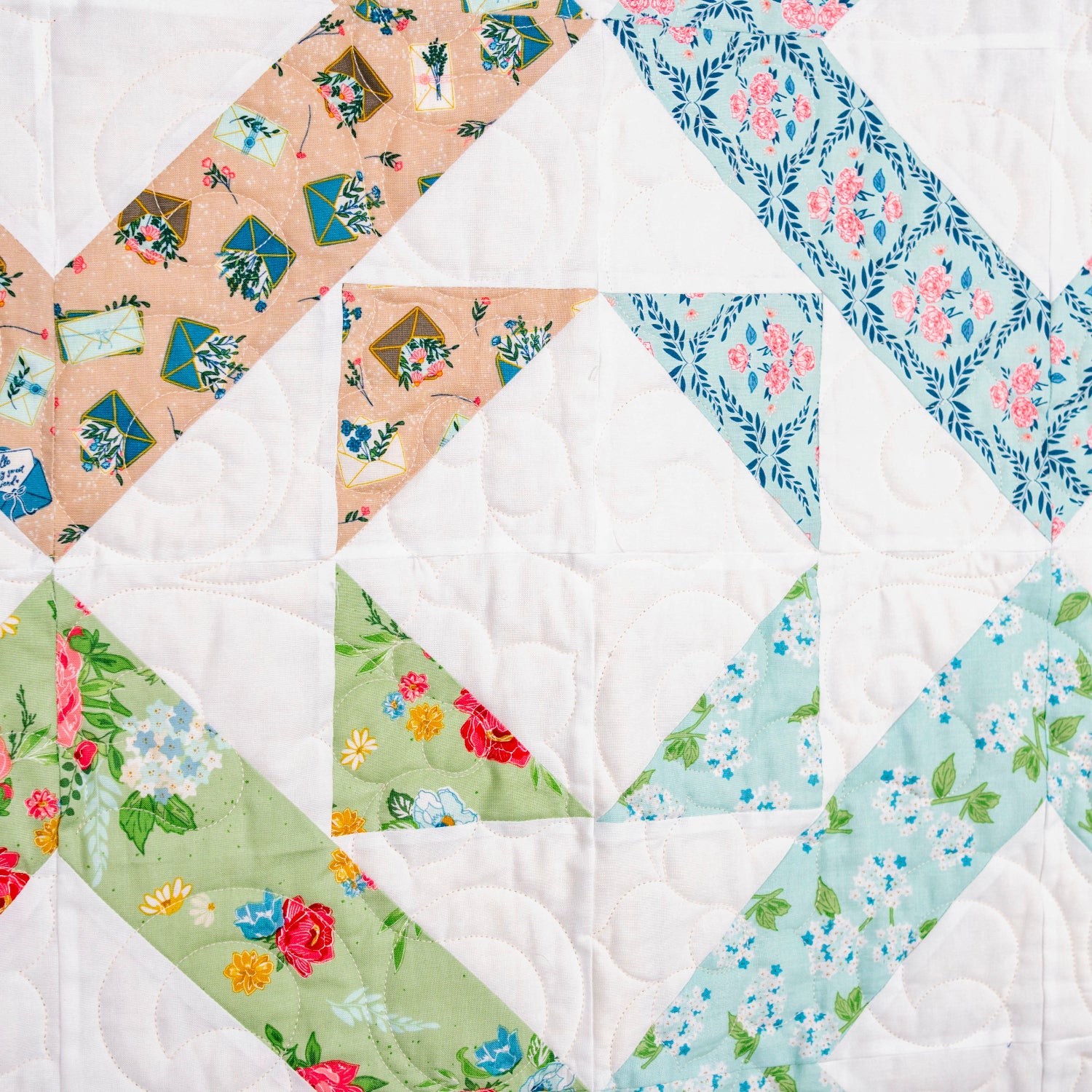 Quilt with diamond pattern featuring various floral fabrics on a white background