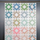 Colorful quilt with geometric patterns hanging on a wall.