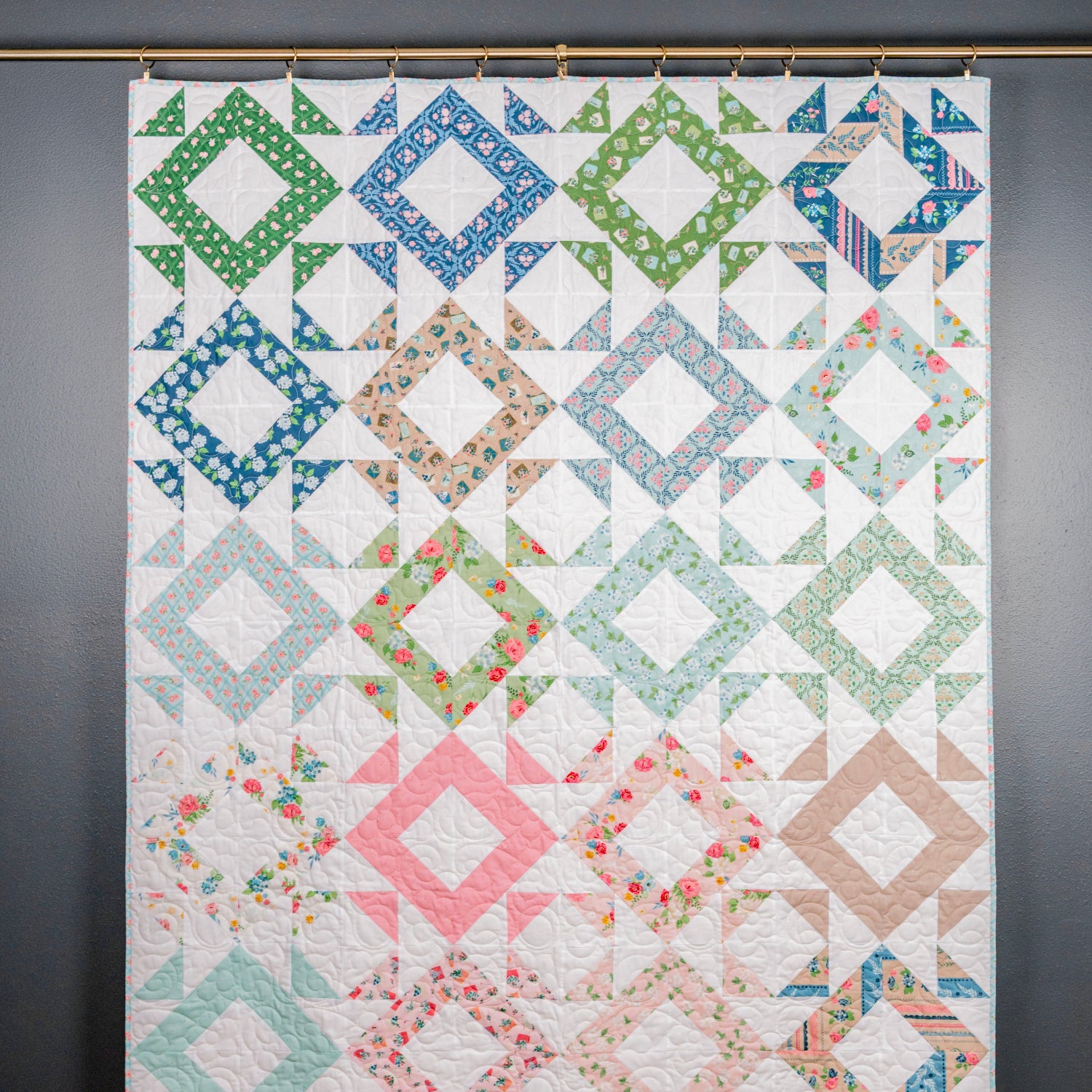 Colorful quilt with geometric patterns hanging on a wall.