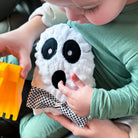 Child holding a plush ghost toy in a car seat