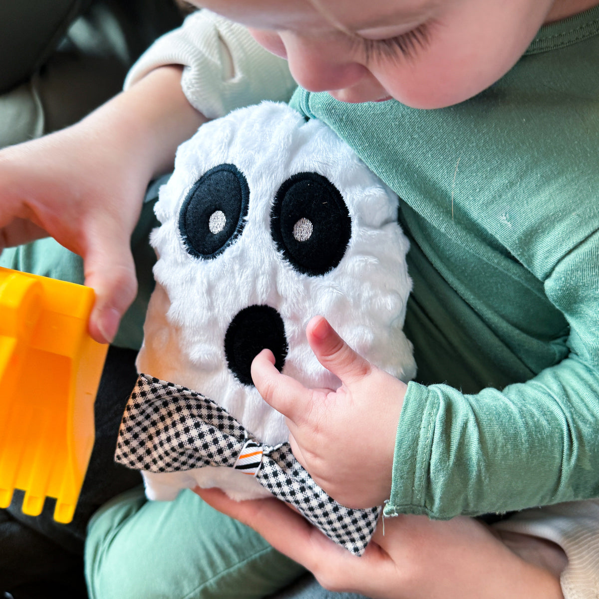Child holding a plush ghost toy in a car seat