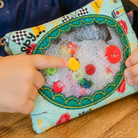 Children's hand holding a colorful fabric pouch with a textured interior