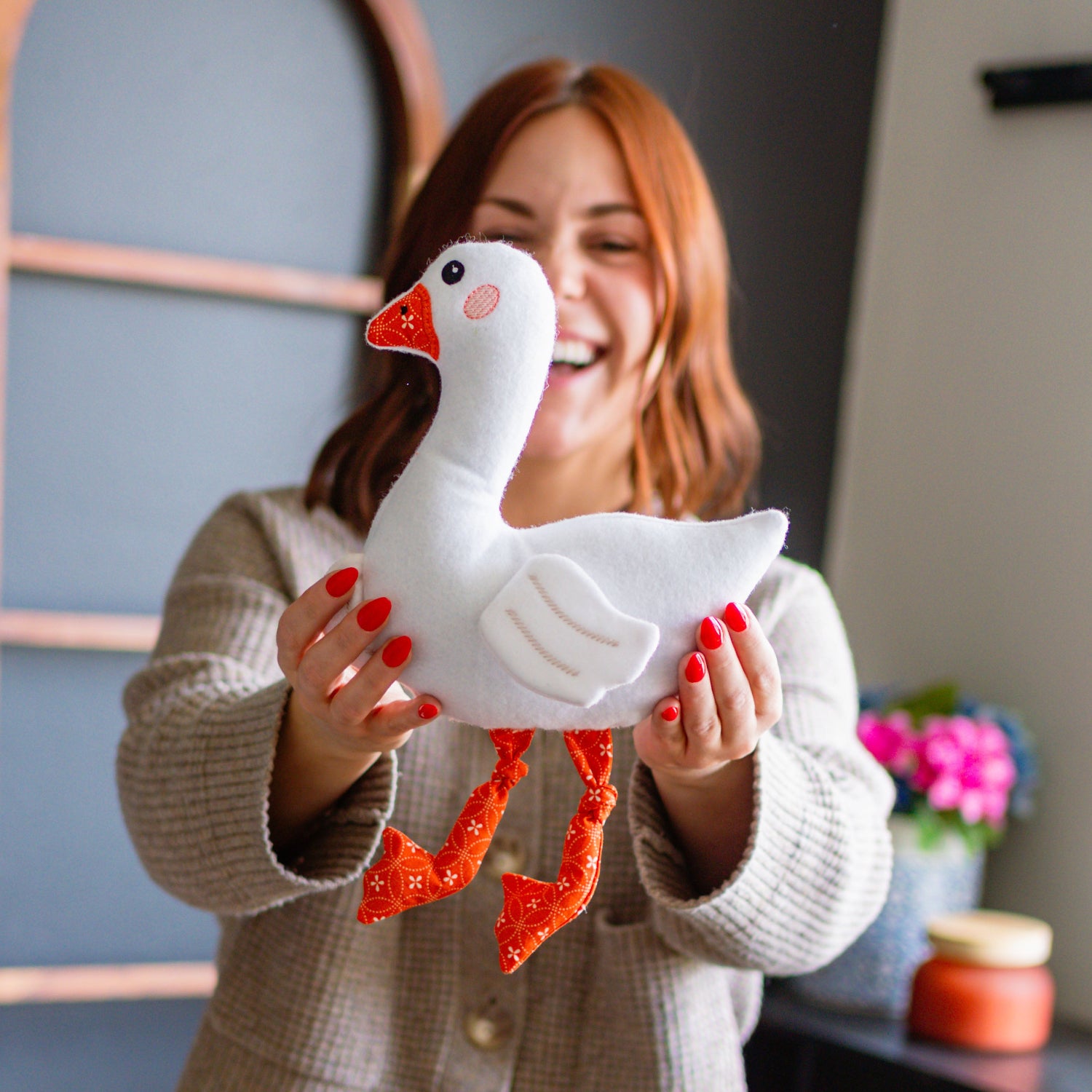Woman holding a white goose-shaped pillow in a room with decor elements.