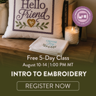 Promotional graphic for an intro to embroidery free class, featuring a decorative embroidered pillow that reads 'Hello Friend' and a folded embroidered cloth that says 'Choose Joy'. A lit candle and books sit on a wooden surface, with large text advertising a free 5-day class and a registration button.