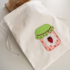 Drawstring bag with strawberry-themed design on a white surface