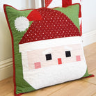 Quilted Santa Claus pillow on a wooden floor with a white wall background