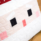 Quilt with a cartoonish face design on a wooden surface