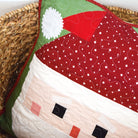 Quilted pillow with a Santa Claus design on a woven surface