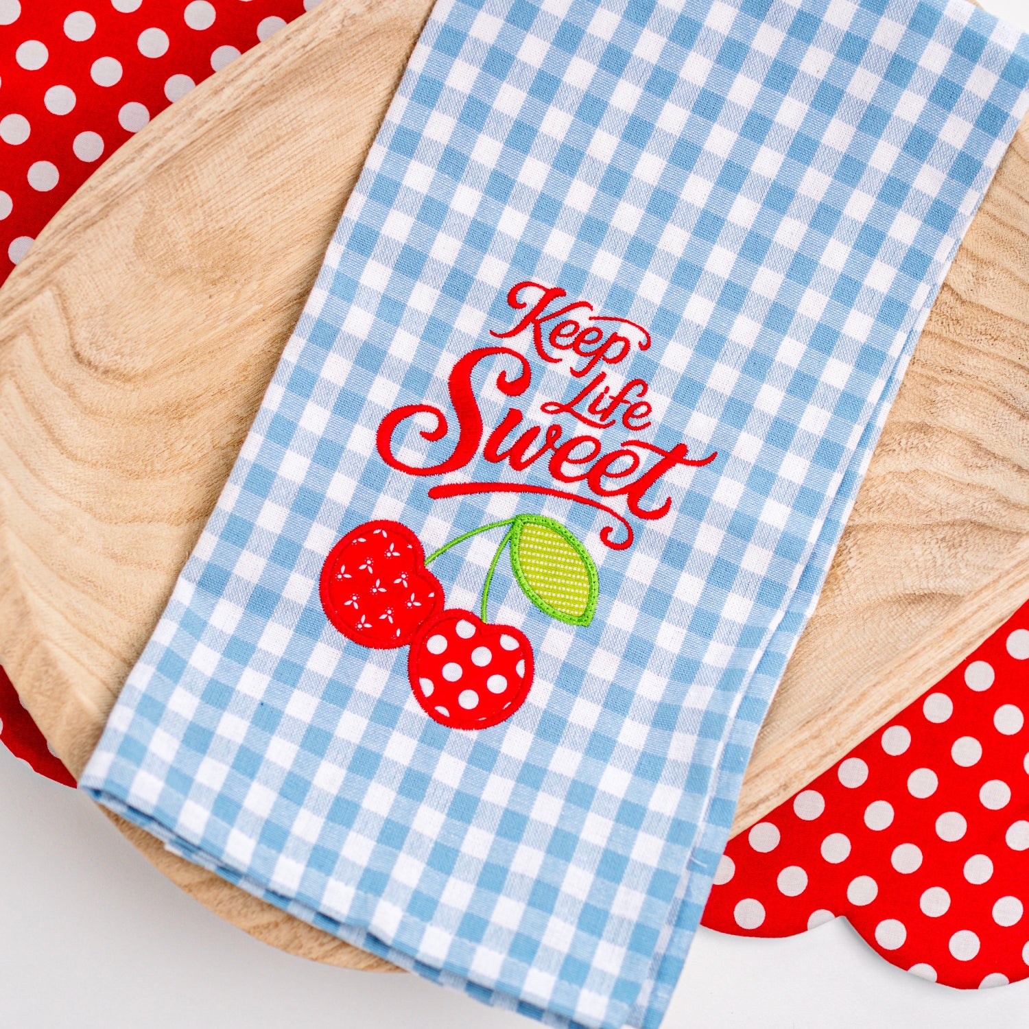 Blue checkered towel with 'Keep Life Sweet' text and cherry design on a red polka dot background.