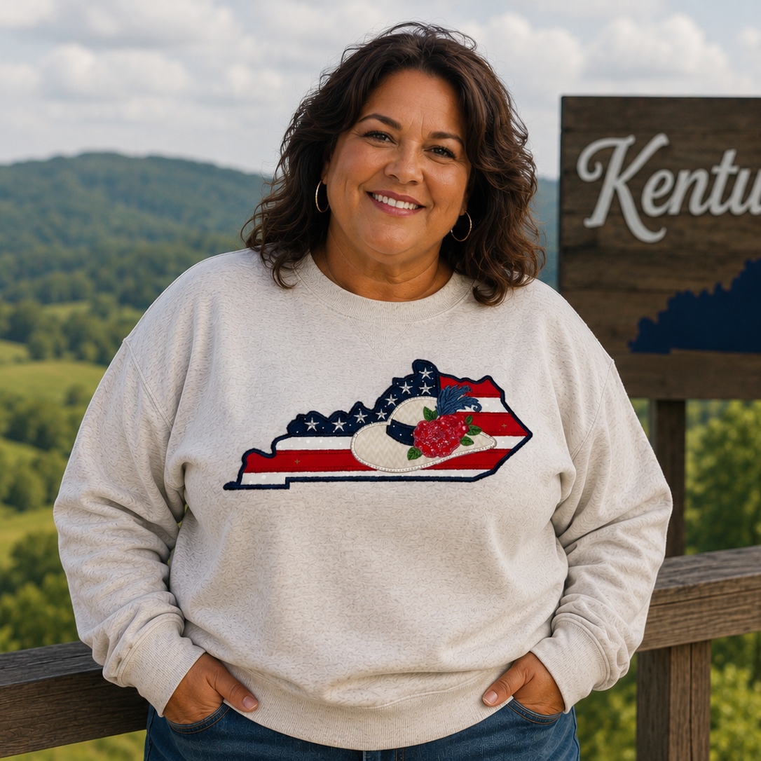 Person wearing a sweatshirt with a Kentucky design in front of a scenic view with a 'Kentucky' sign.