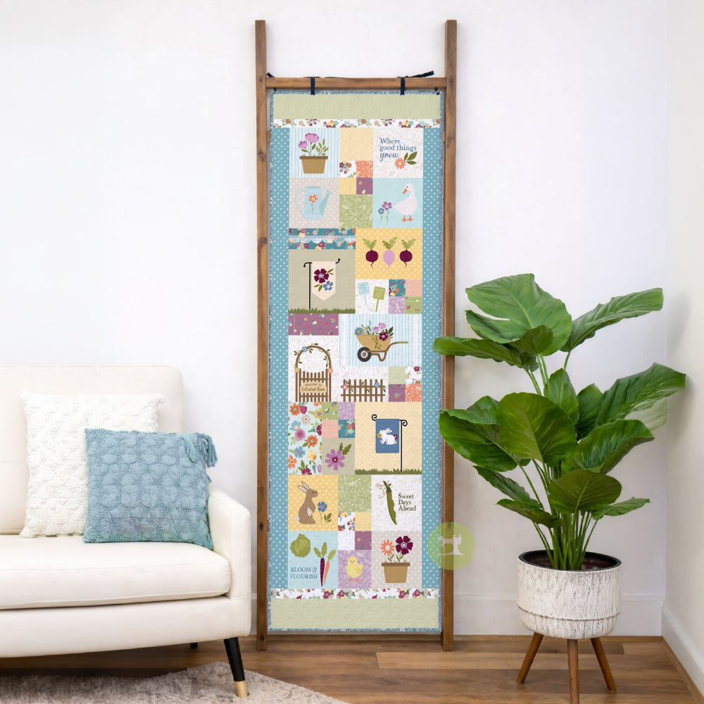 Decorative quilt on a wooden ladder in a living room setting with a plant and sofa.