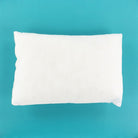A plain white rectangular pillow or cushion shown from above on a bright turquoise-blue background.