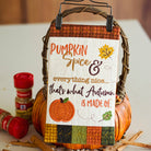 A decorative autumn-themed sign hanging from a wicker basket handle, with the phrase “Pumpkin Spice & everything nice.