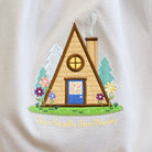 Embroidered A-frame cabin design on a white fabric background with 'Sew Simple Sew Happy' text.