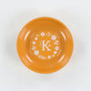 Orange plate with white floral and letter 'K' design on a white background