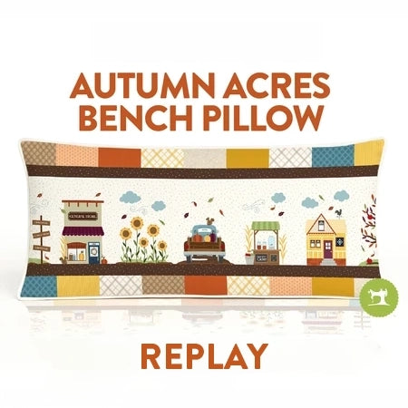 Autumn Acres Bench Pillow shown in a replay view with the text 'AUTUMN ACRES BENCH PILLOW' at the top and 'REPLAY' at the bottom. The pillow features a colorful autumn-themed illustration with a patchwork border and small houses, trees, and sunflowers.