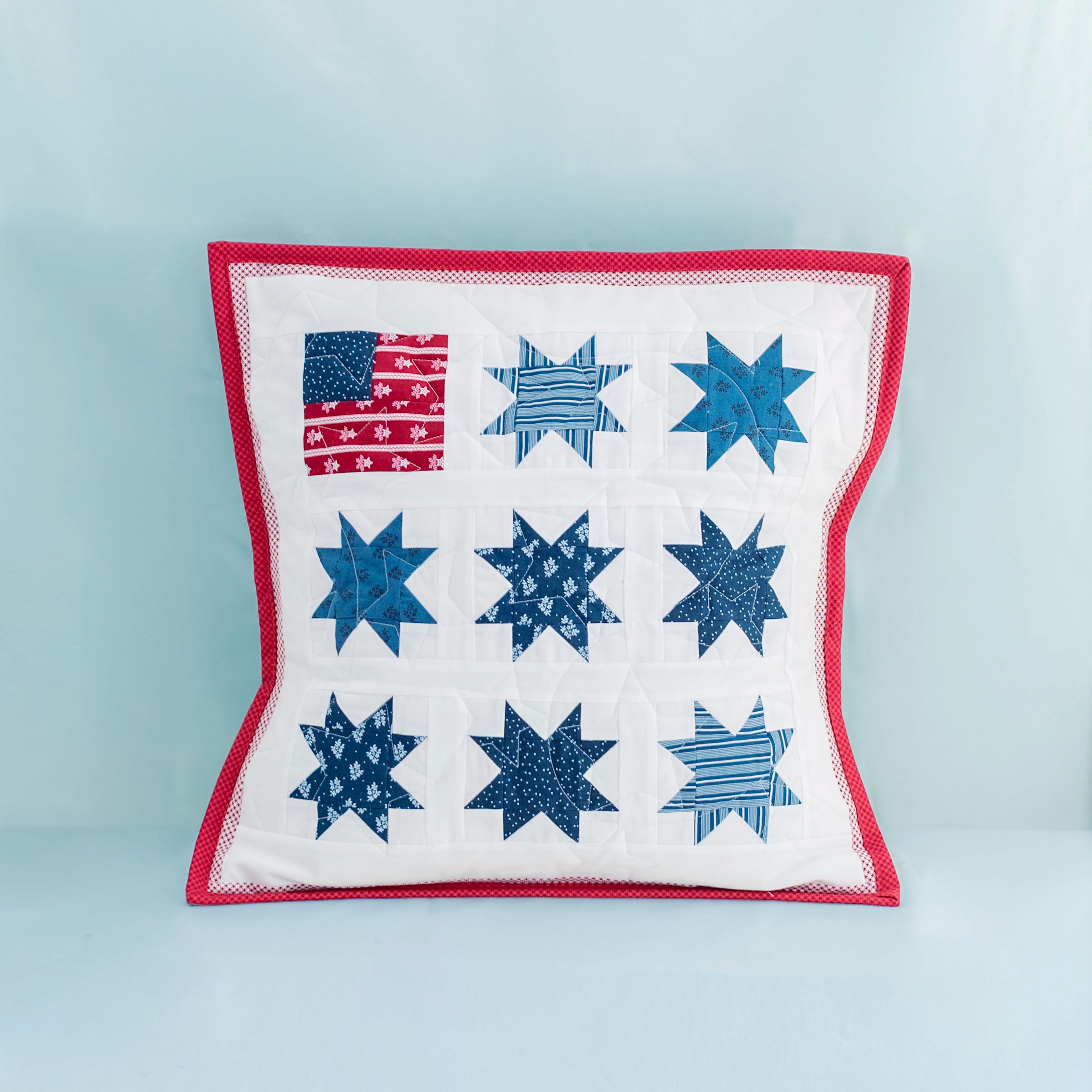 Decorative pillow with star pattern and American flag on a light blue background