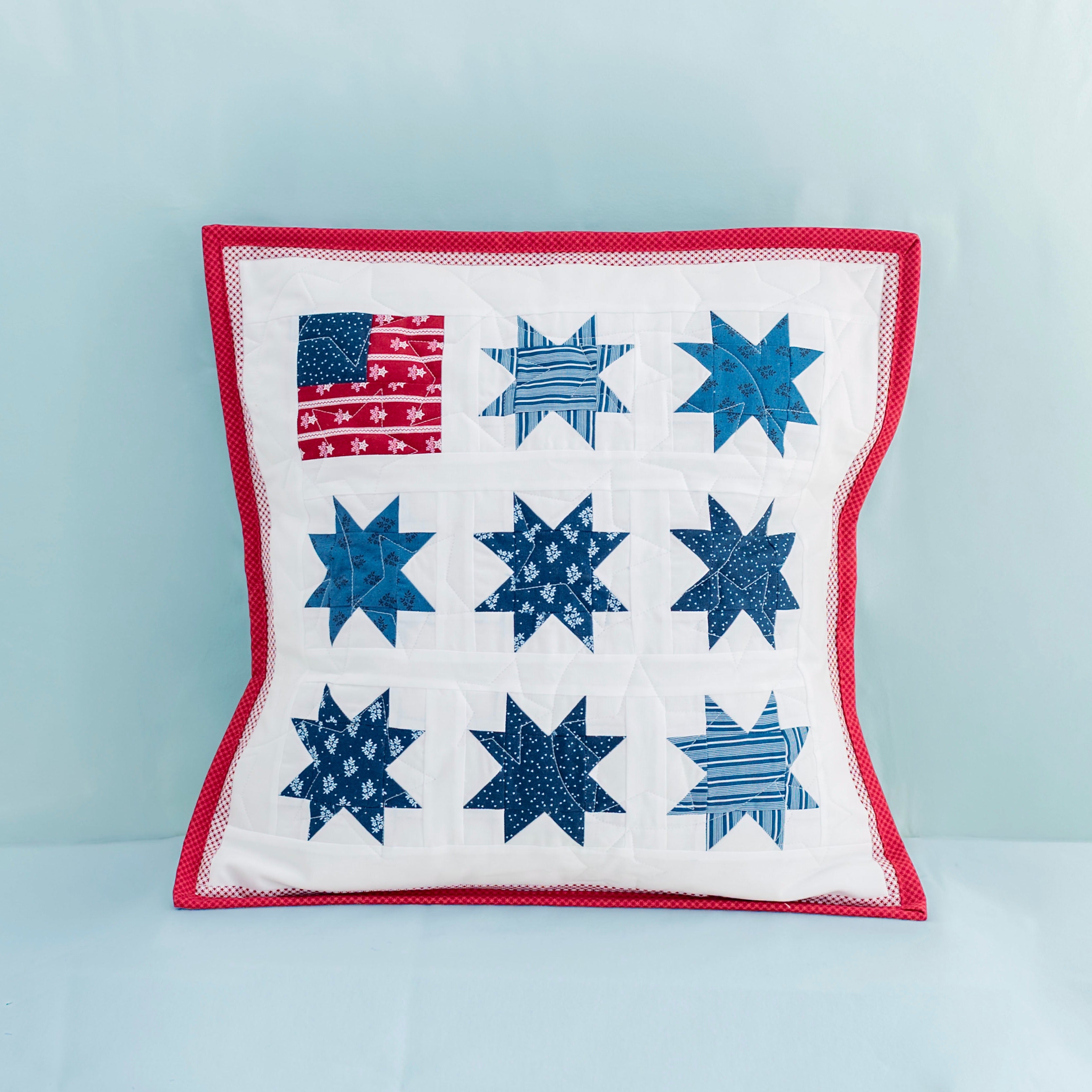 Decorative pillow with star pattern and American flag on a light blue background