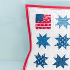 Quilted pillow with American flag and star patterns on a light blue background