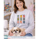 Woman wearing a sweatshirt with embroidery design sitting with a dog in a sewing room.