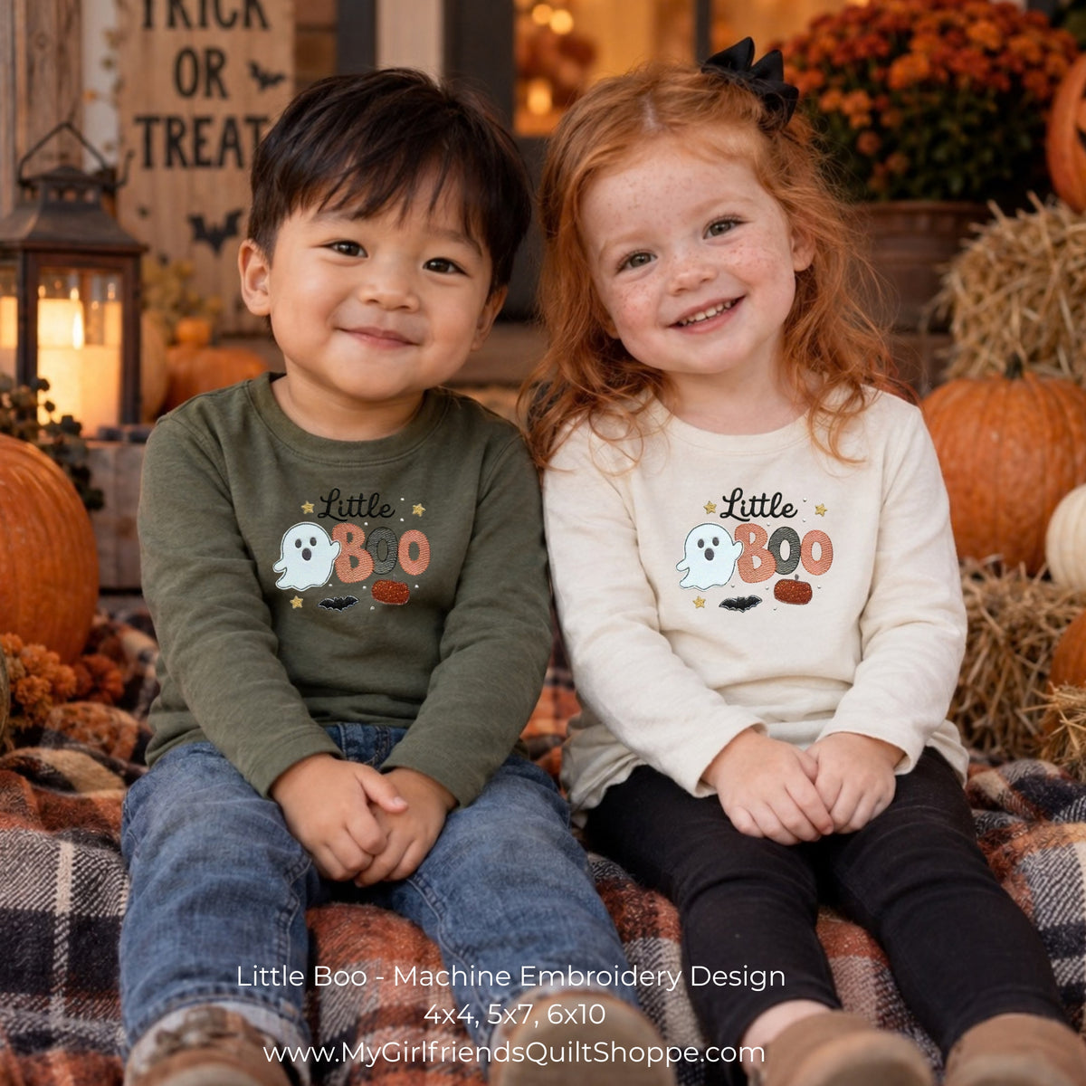 Two children sitting side by side in a fall-themed setting, wearing matching long-sleeve shirts with a 'Little Boo' machine embroidery design featuring a ghost, pumpkin, and bats.