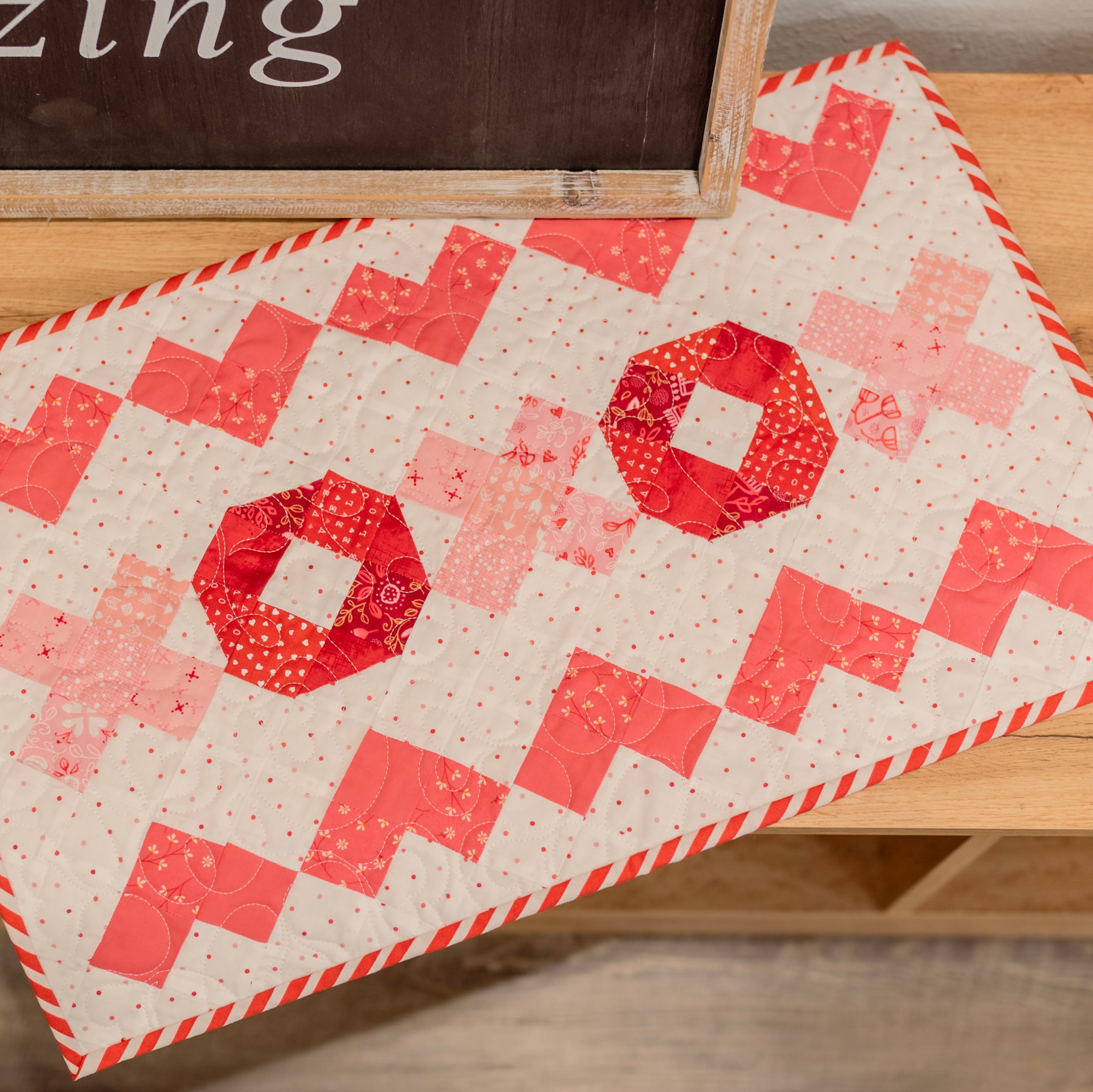Quilt with red and pink pattern on a wooden surface