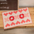 Quilt with red and white pattern on a wooden surface