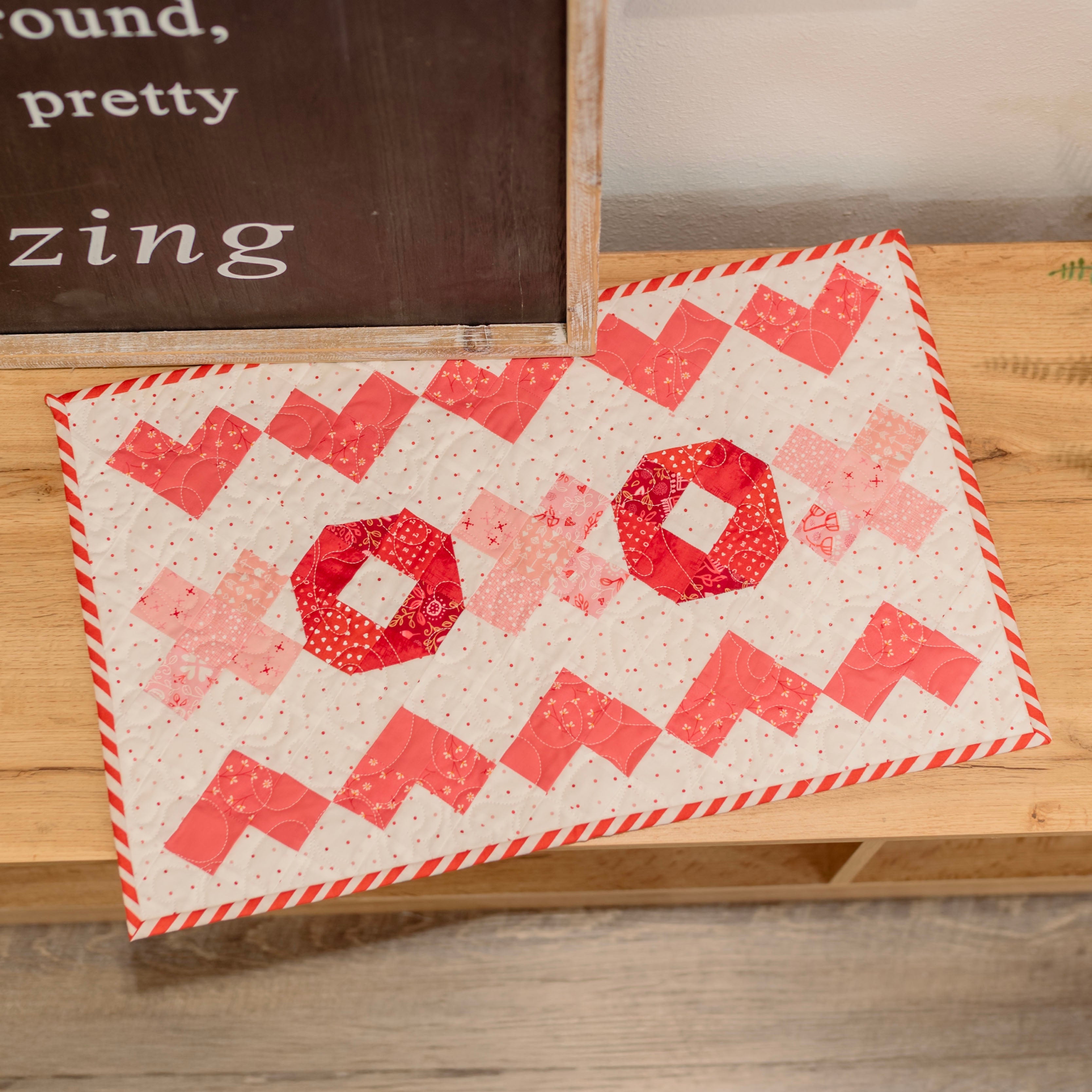 Quilt with red and white pattern on a wooden surface