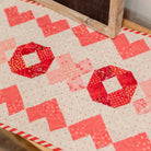Quilt with red and pink geometric pattern on a wooden surface