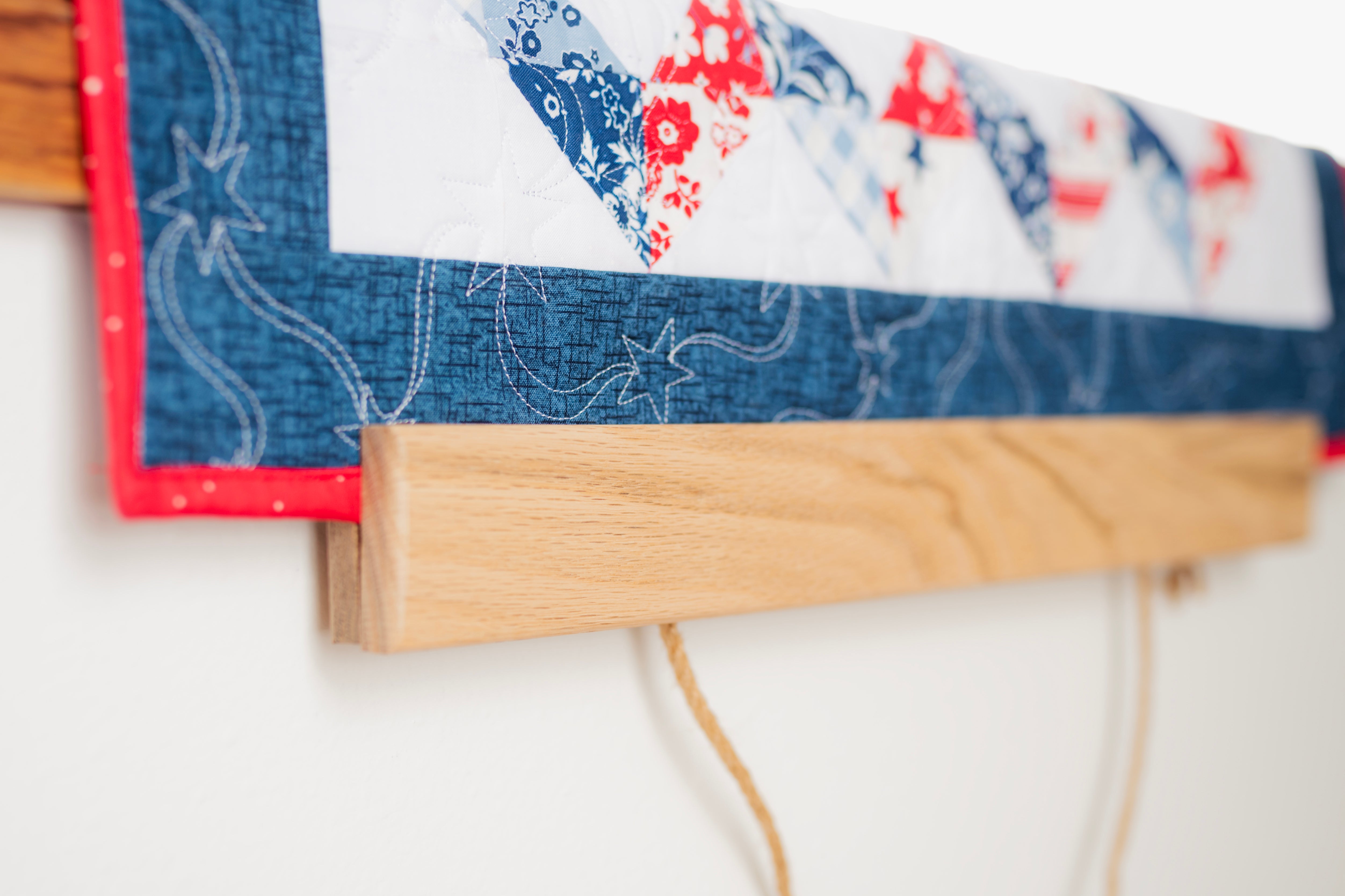 Close-up of a quilt with floral patterns and denim border on a white background 18" wall hanger