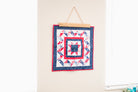 Quilt with a red, white, and blue pattern hanging on a wall. 18" wall hanger
