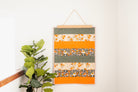 Colorful striped wall hanging with floral patterns on a white wall. 24" wall hanger