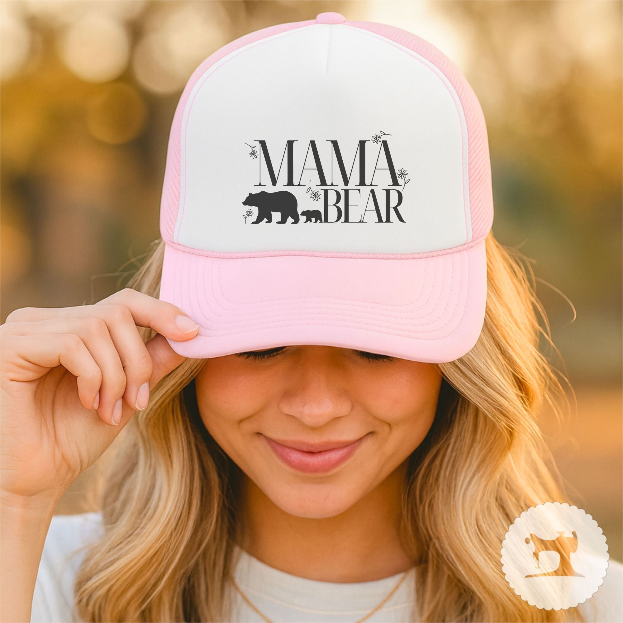 Person wearing a pink 'Mama Bear' cap with a blurred natural background