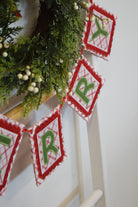 Christmas-themed banner with red and green triangles hanging against a white wall.