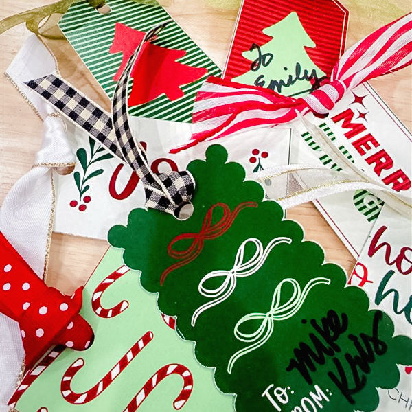 Collection of Christmas-themed gift tags with ribbons on a wooden surface