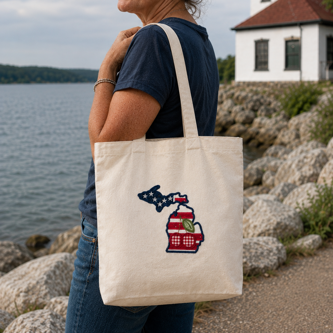 Woman holding a tote bag with a Michigan-themed design by a lighthouse.