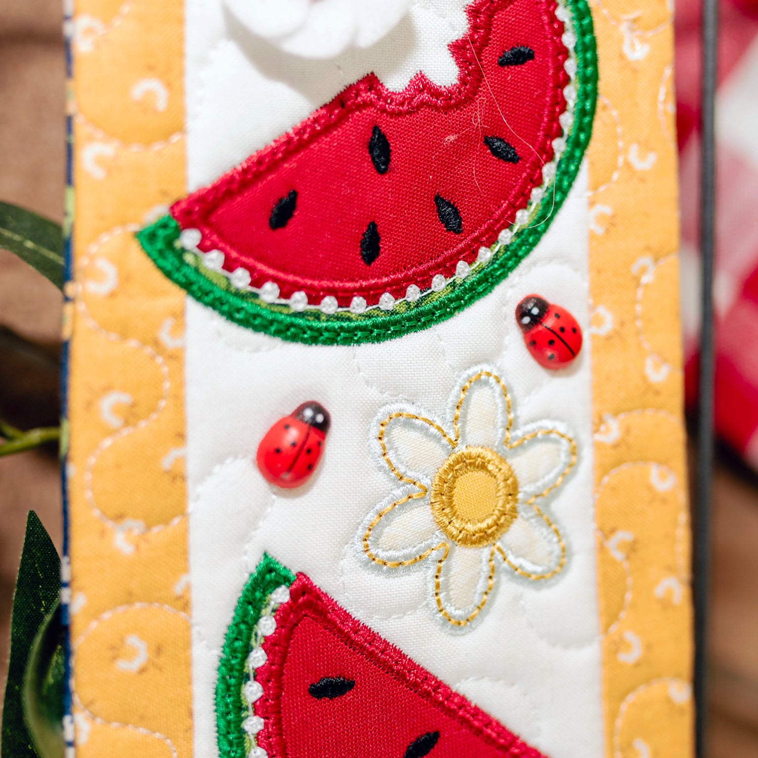 Decorative fabric panel with watermelon slices, ladybugs, and a flower on a striped background.