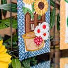 Decorative wall hangings with sunflower, house, and watermelon designs on a blue and yellow background.