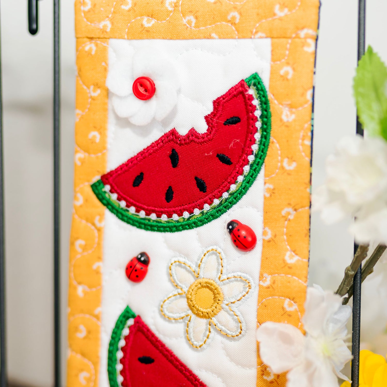 Decorative phone case with watermelon slice, sunflower, and ladybug design on a white background.