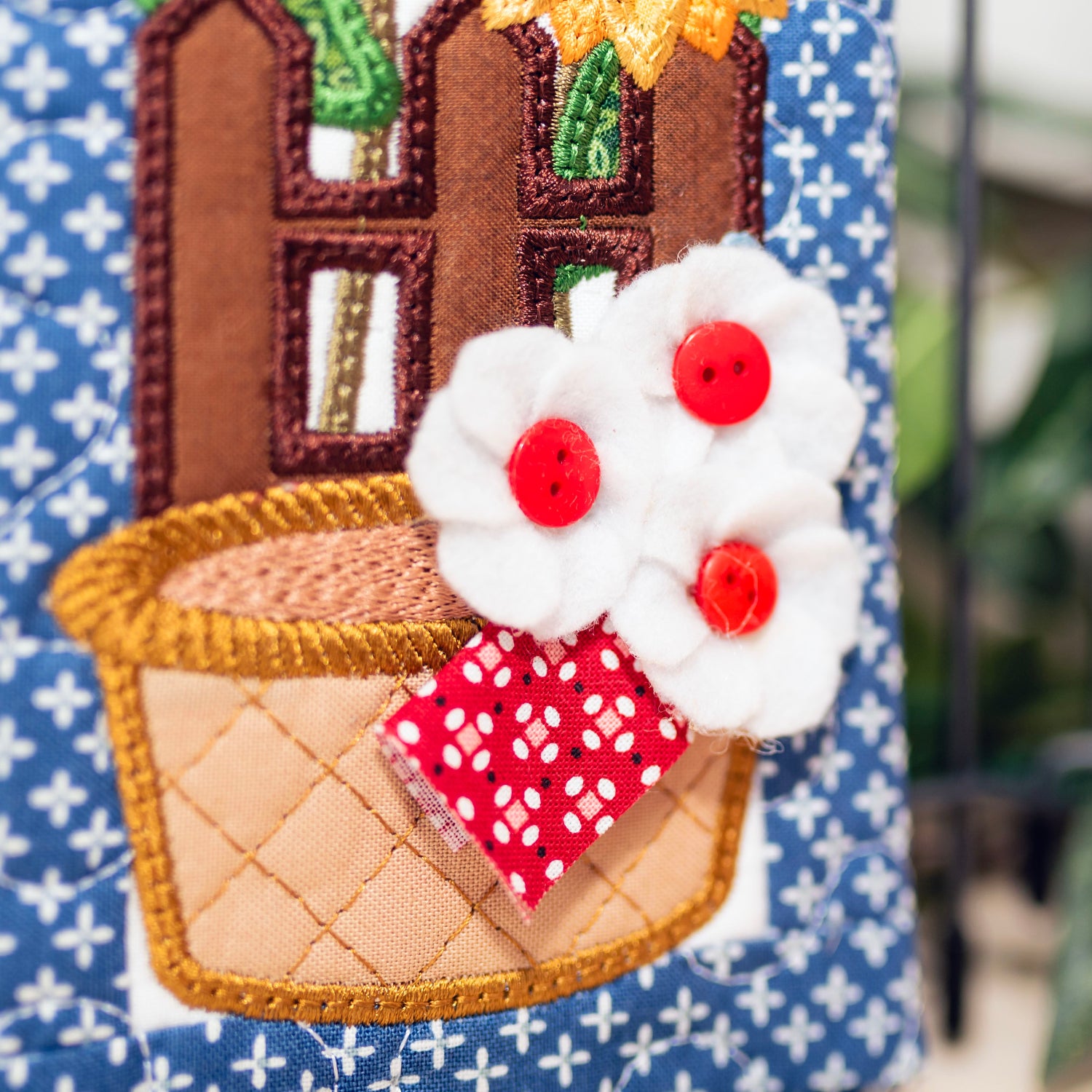 Decorative item with a house, flower, and basket design on a blue background.