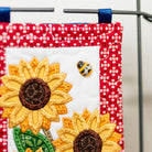 Decorative wall hanging with sunflowers and a bee on a red and white polka dot background.
