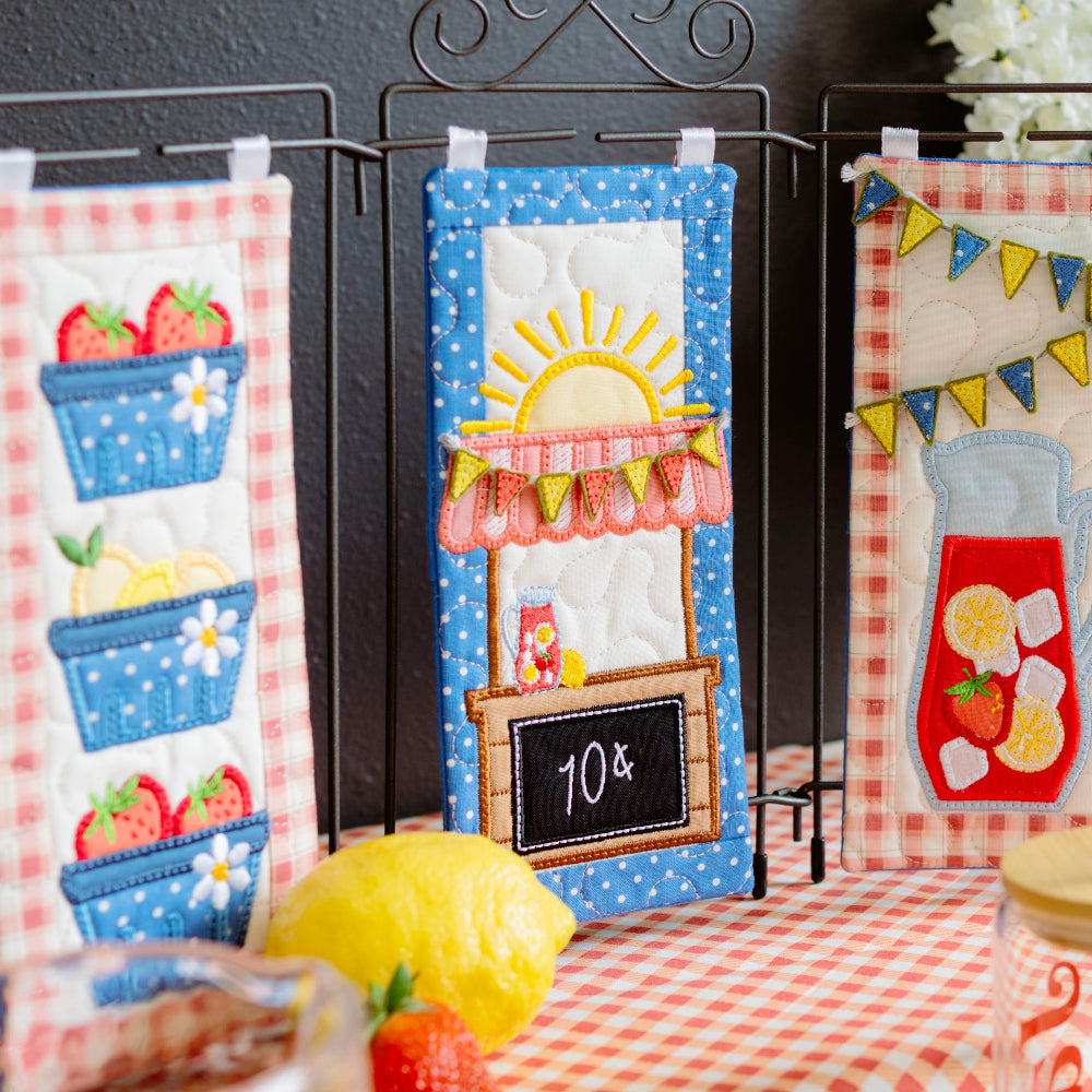 Decorative kitchen towels with summer-themed designs on a table.