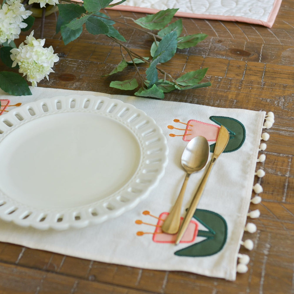 White plate on a decorative placemat with floral design on a wooden table.