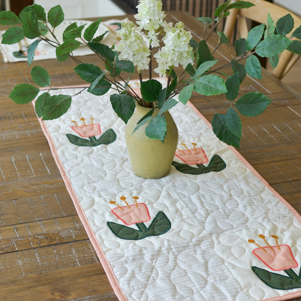 Quilted table runner with floral design on a wooden table