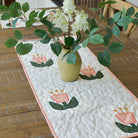 Quilted table runner with floral design on a wooden table