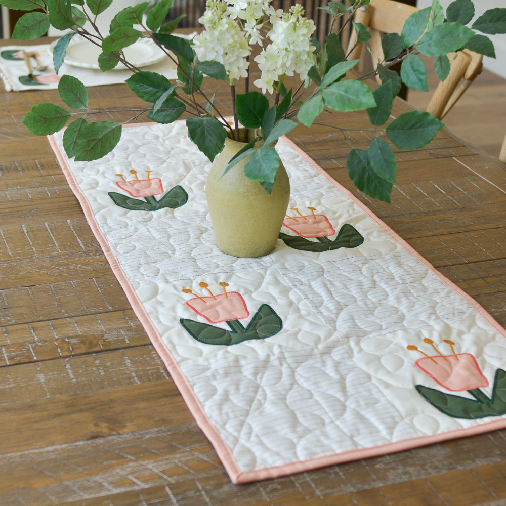 Quilted table runner with floral design on a wooden table